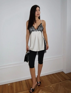 Detail view of a white silk camisole with black lace trim and fitted black cycling shorts