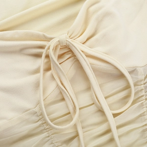 Close-up of beige knit T-shirt featuring mesh patchwork and drawstring ruched details