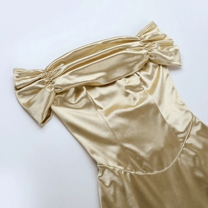 Detail of champagne gold satin strapless dress showing smooth glossy fabric and pleats