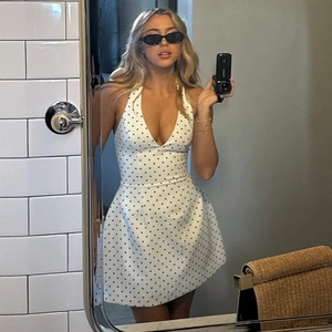 Detail of halter neck V-neck mini dress with ivory and black polka dot pattern