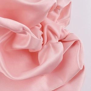 Close-up detail of smooth pink satin fabric with elegant folds and glossy texture on a dress