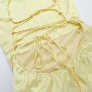 Detail of cross-back tie design and bow on a yellow satin backless A-line dress