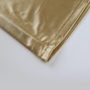 Detailed macro view of the double-stitched hem on the gold metallic A-line dress fabric