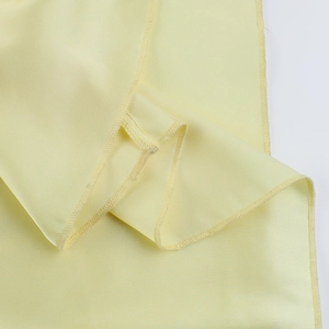 Detail of high-quality overlock stitching on light yellow chiffon puff dress fabric