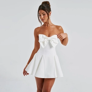Detail of white off-the-shoulder mini dress featuring a large bow and pleated skirt