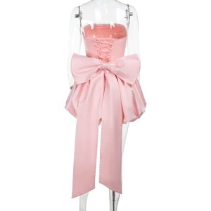 Lace-up back detail of a pink satin dress featuring a large bow and adjustable corset ties