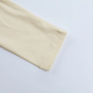 Detailed close-up of double-stitched cuff on a cream-colored slim-fit knit T-shirt