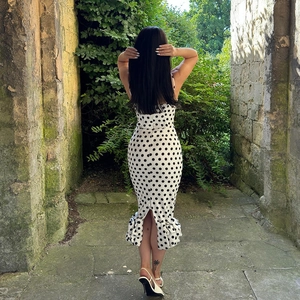 Detail of slim fit polka dot midi dress showing fishtail hem and ruffled back slit