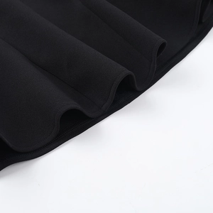 Detailed macro view of the wavy hemline and thick knit fabric texture of the black dress