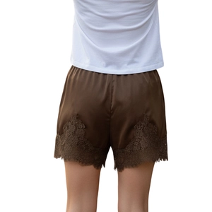 Detail view of the back of dark brown satin shorts with delicate lace trim on the hem
