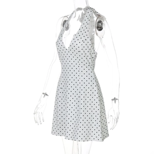 Detail view of the white halter neck dress with black polka dots and a deep V-neckline