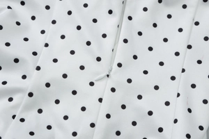 Macro detail of white polka dot fabric featuring a seamless invisible zipper closure
