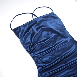 Detail view of navy blue satin dress showing elegant side ruching and glossy fabric texture