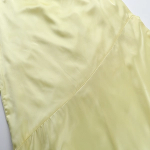 Detailed view of pale yellow satin fabric with smooth texture and neat diagonal stitching