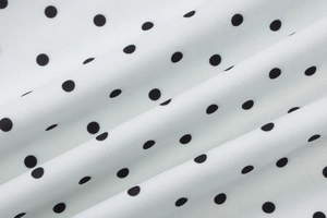 Close-up of white chiffon fabric with black polka dots showing soft texture and drape