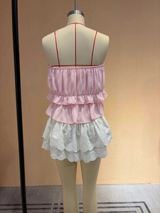 Haut sans manches en mousseline rose à volants avec jupe brodée blanche sur un mannequin