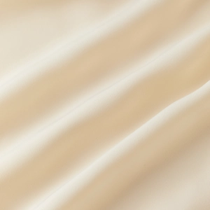 Close-up of premium cream lace fabric with silky texture and elegant draped folds
