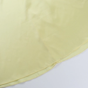 Macro detail of the light yellow dress hem showing professional overlock stitching craftsmanship