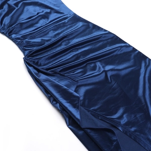 Detail view of smooth dark blue satin fabric with side ruching and a high slit finish