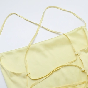 Detailed view of the pale yellow satin camisole with elegant thin crisscross straps