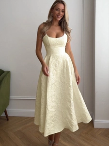 Detailed view of pale yellow jacquard fabric and waistline on elegant midi dress
