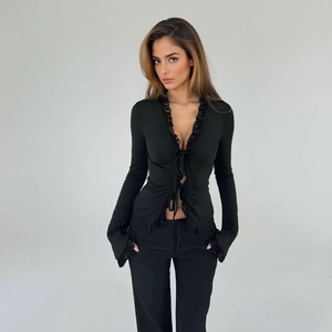 Detailed view of the V-neckline with delicate black lace trim and front tie closure