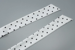 Detailed macro view of white silk ribbon with black polka dots and slanted edges