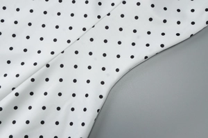 Detailed macro view of white fabric with black polka dot pattern and smooth texture