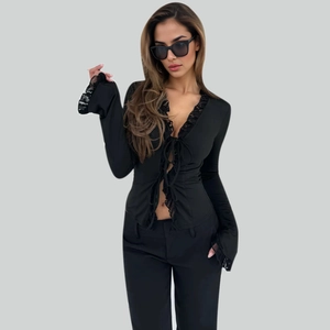 Detail of black chiffon top featuring deep V-neck with lace trim and cross-tie front closure