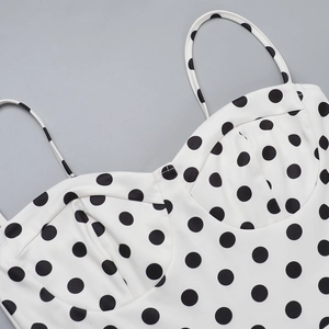 Close-up of white dress with black polka dots featuring thin straps and pleated bust detail