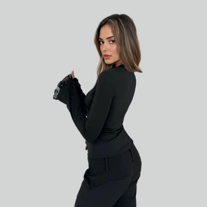 Detail of elegant black slim-fit top featuring delicate lace trim on flared cuffs