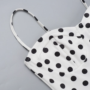 Detail of white dress with black polka dots featuring delicate straps and structured cups