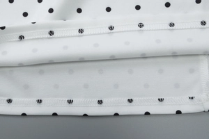 Detail of the double-needle hem stitching on white polka dot summer dress fabric