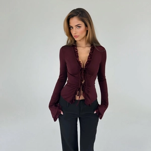 Detail of burgundy V-neck cardigan featuring lace trim and front tie decoration