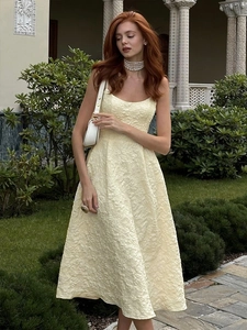 Detailed close-up of yellow jacquard fabric and elegant A-line silhouette of the midi dress