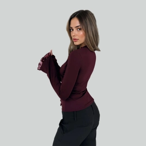 Detail of burgundy chiffon blouse showing elegant ruffled cuffs and stand collar design