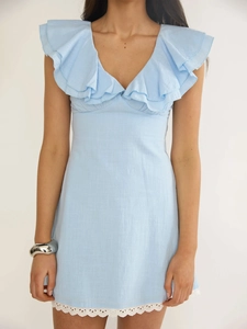 Détail d'une robe bleu clair col en V avec volants et ourlet en dentelle blanche
