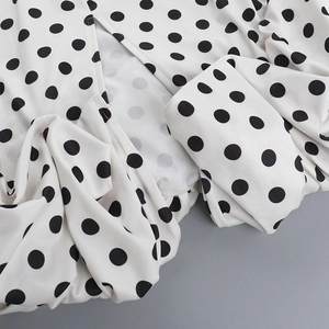 Detail of white polka dot fabric showing delicate stitching and chiffon texture