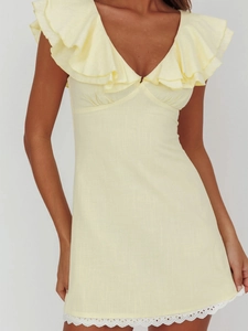 Détail du col en V à volants et de l'ourlet en dentelle blanche sur robe en lin jaune