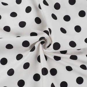 Detailed close-up of white fabric with black polka dots showing smooth drape and texture