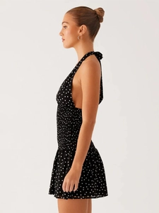 Detail of polka dot halter dress featuring ruched waist and flowing A-line silhouette