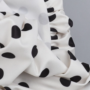 Detailed view of white fabric with black polka dots featuring delicate ruffled edges