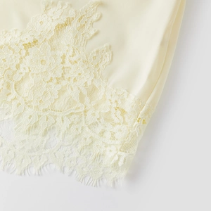 Detailed view of cream silk shorts featuring delicate lace trim and eyelash fringe edges