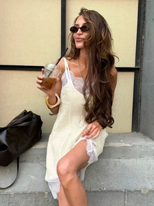 Pale yellow lace-trim slip dress with side slit detail shown in an outdoor street setting
