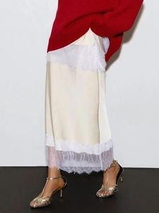 Dettaglio della gonna midi in raso beige con bordo in pizzo bianco dal design elegante