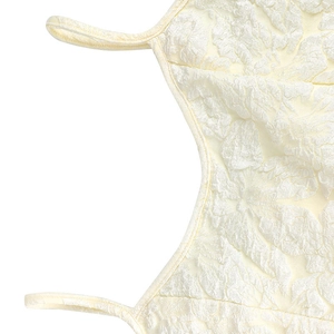 Detail of cream white dress showing high-quality floral jacquard fabric and thin straps