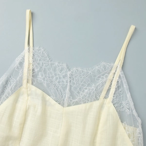 Detailed macro view of delicate white lace trim on a cream-yellow camisole dress neck