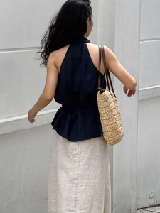 Detail of elegant navy halter neck top with ruffle hem and rustic straw tote bag