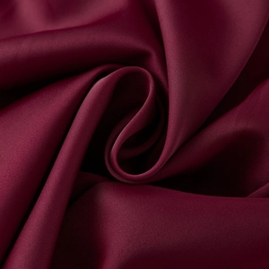 Detailed close-up of dark red satin fabric texture with elegant silky folds and glossy finish