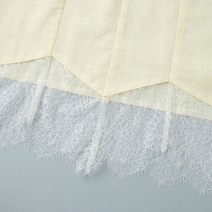 Close-up of cream lace hem with eyelash details and textured linen fabric stitching